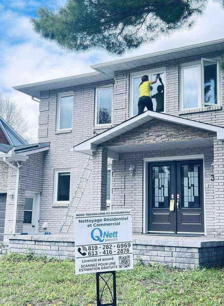QNett Services technician cleaning windows at a Gatineau home with company sign visible